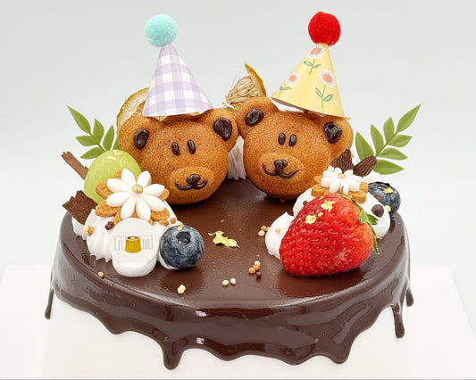 Two bear-shaped madeleines on a chiffon cake with decorative elements.