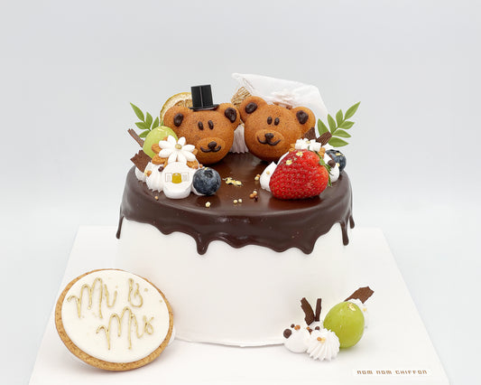 Chiffon cake with teddy bear madeleines and a 'Mr & Mrs' cookie on a white background