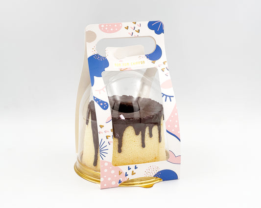 small chiffon cake with chocolate drip in a decorative packaging with colorful design on a white background