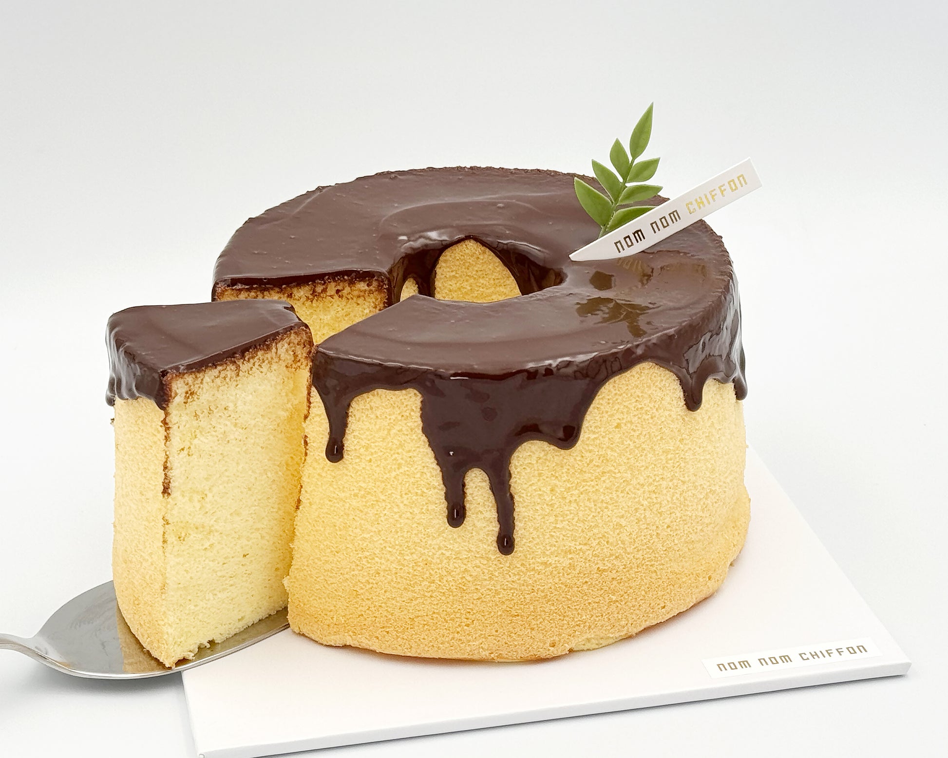 Naked orange zest chiffon cake topped with chocolate ganache, chocolate drip, sliced