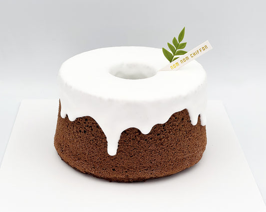 Chocolate chiffon cake with white snowcap frosting on a white background
