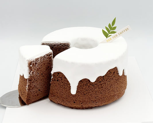 Chocolate chiffon cake with white frosting on a white background