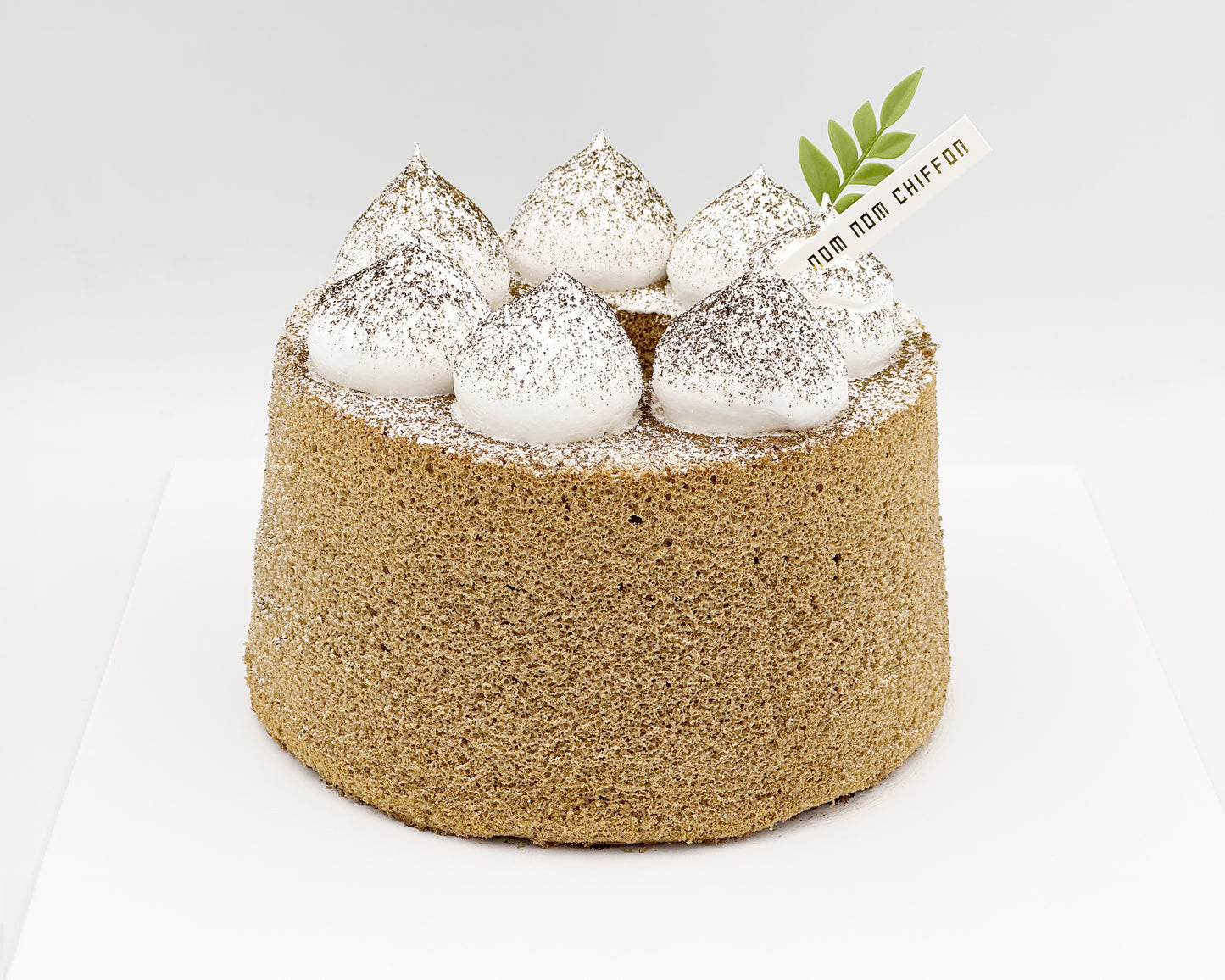 Earl grey chiffon cake with large dollops of cream set on a light gray background