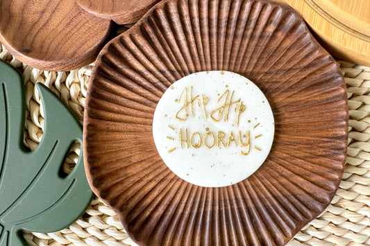 cake topper 'Hip Hip Hooray' text on a woven surface