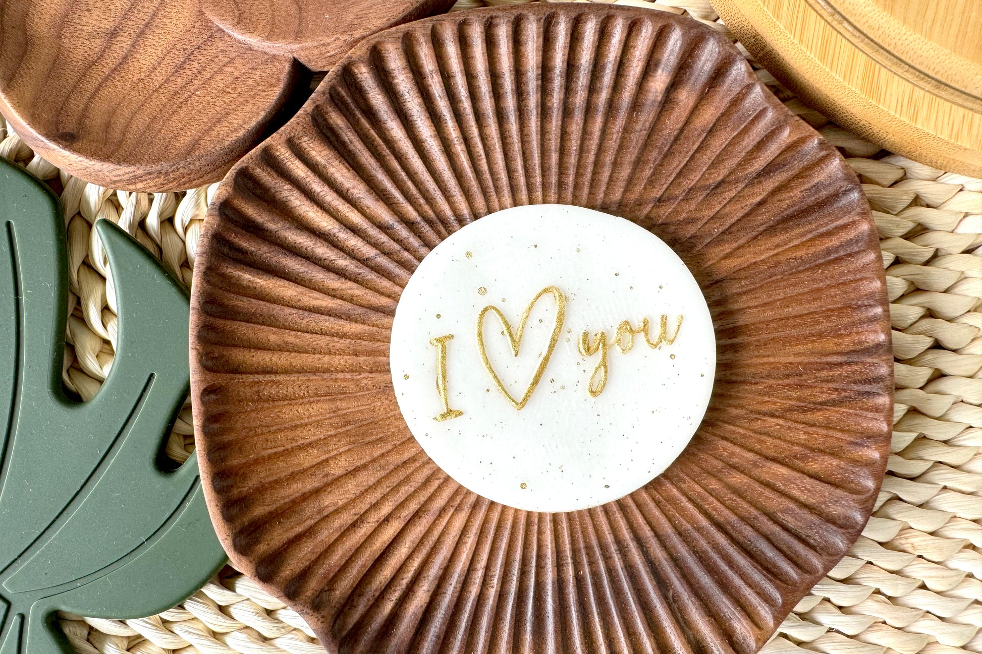 Decorative wooden plate with 'I love you' cake topper on a woven surface