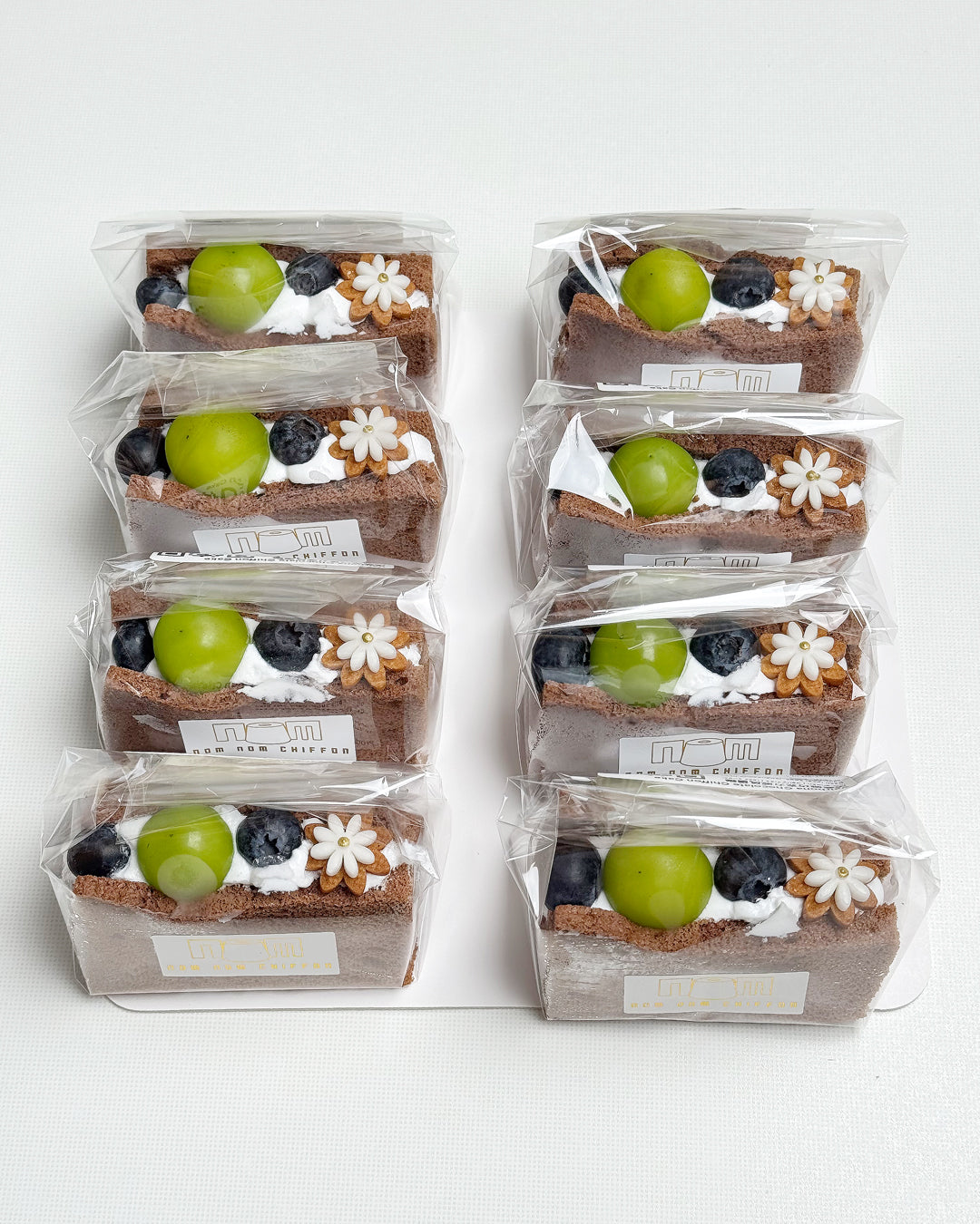 Packaged chocolate chiffon fruit sando in clear plastic wrap on a white background