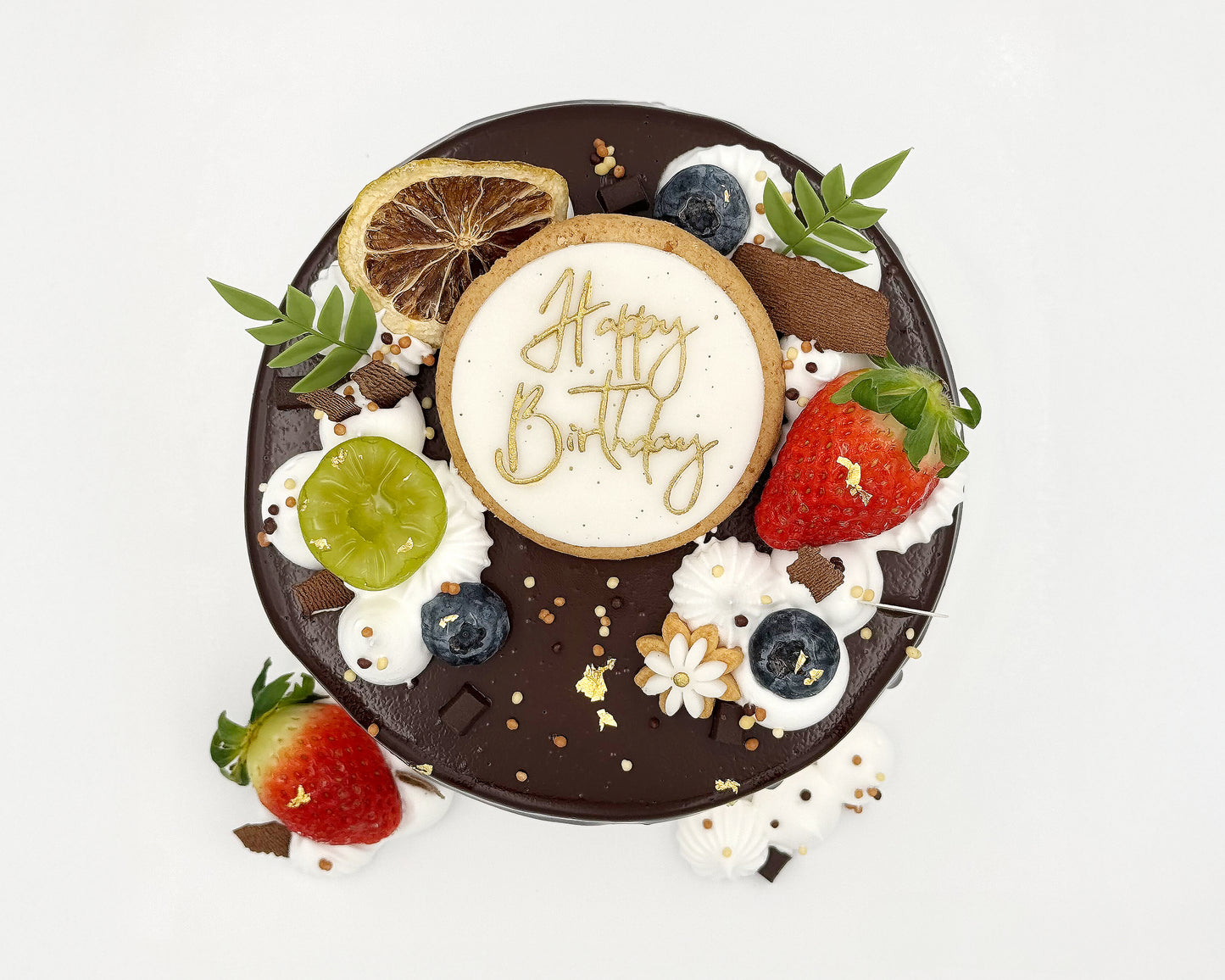 Top view of decorative birthday cake with fruit and 'Happy Birthday' text on a white background