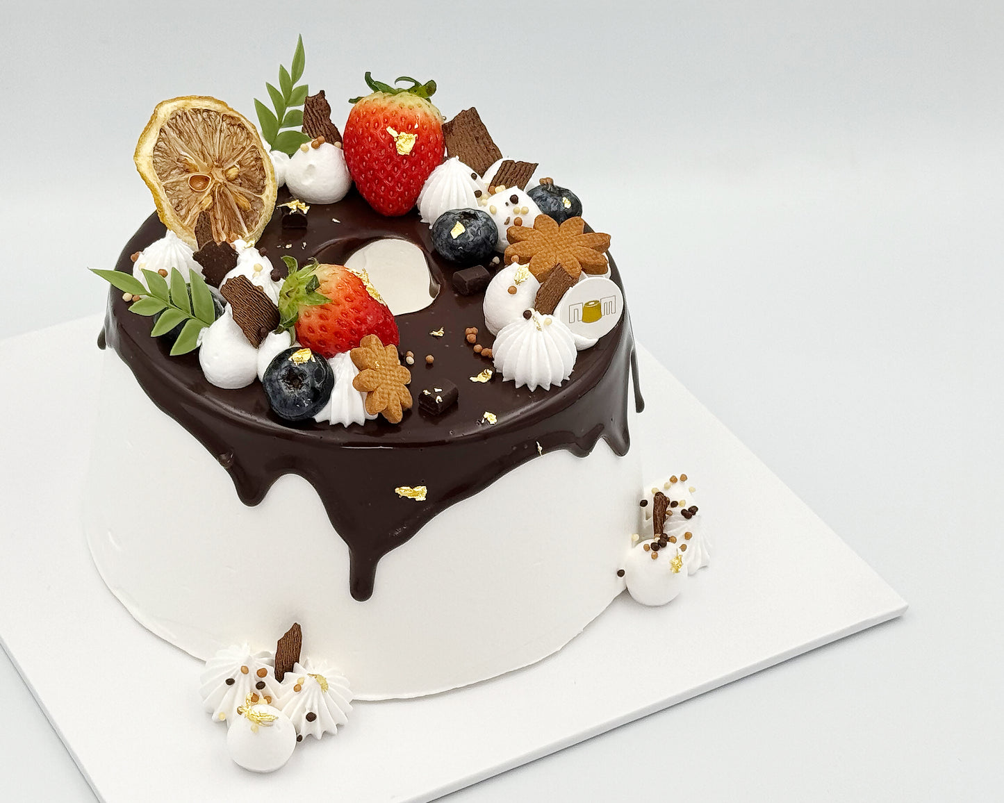 Decorative cake with chocolate ganache, fruits, and cookies on a white background