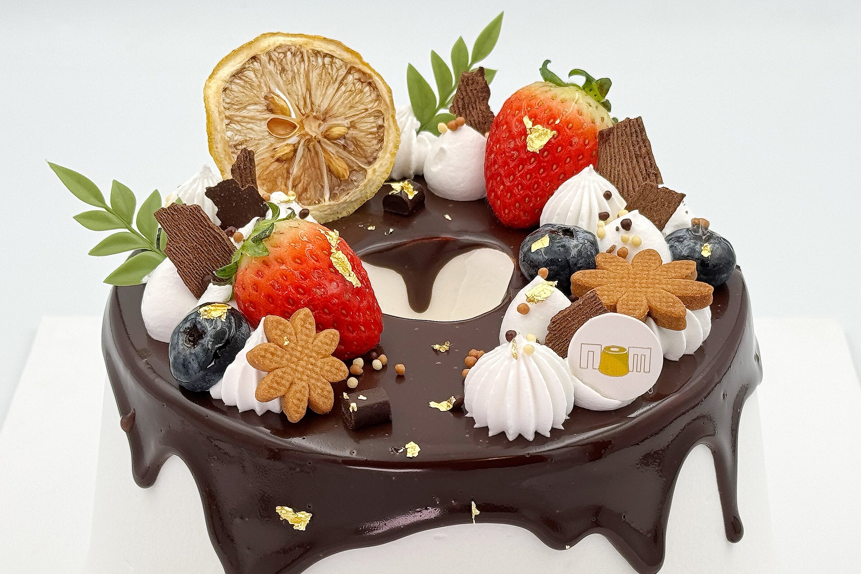 Decorative cake with chocolate, strawberries, blueberries, and cookies on a white background