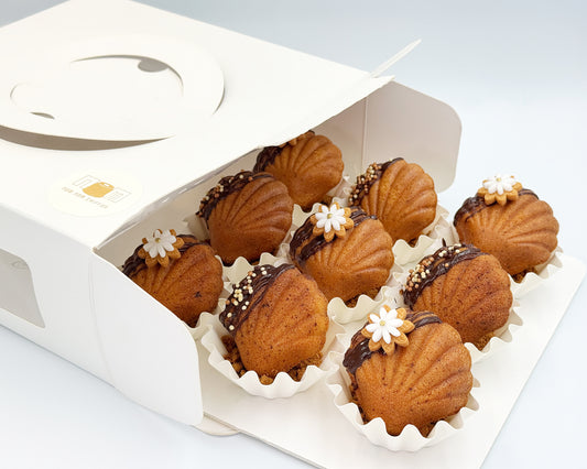 Box of  madeleines with chocolate and decorative elements on a white background