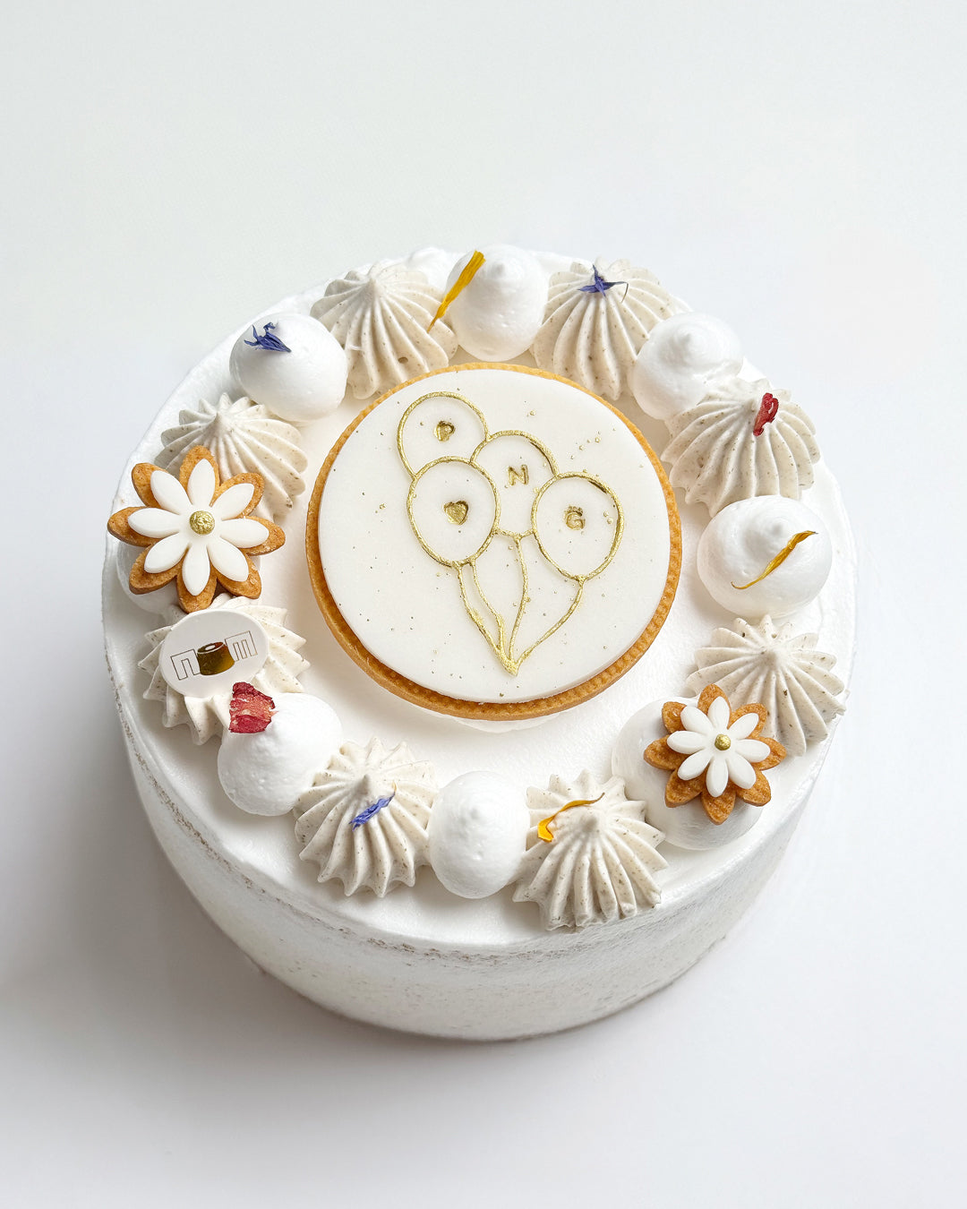 Decorative cake with white frosting, cookies, and a round design on a light gray background