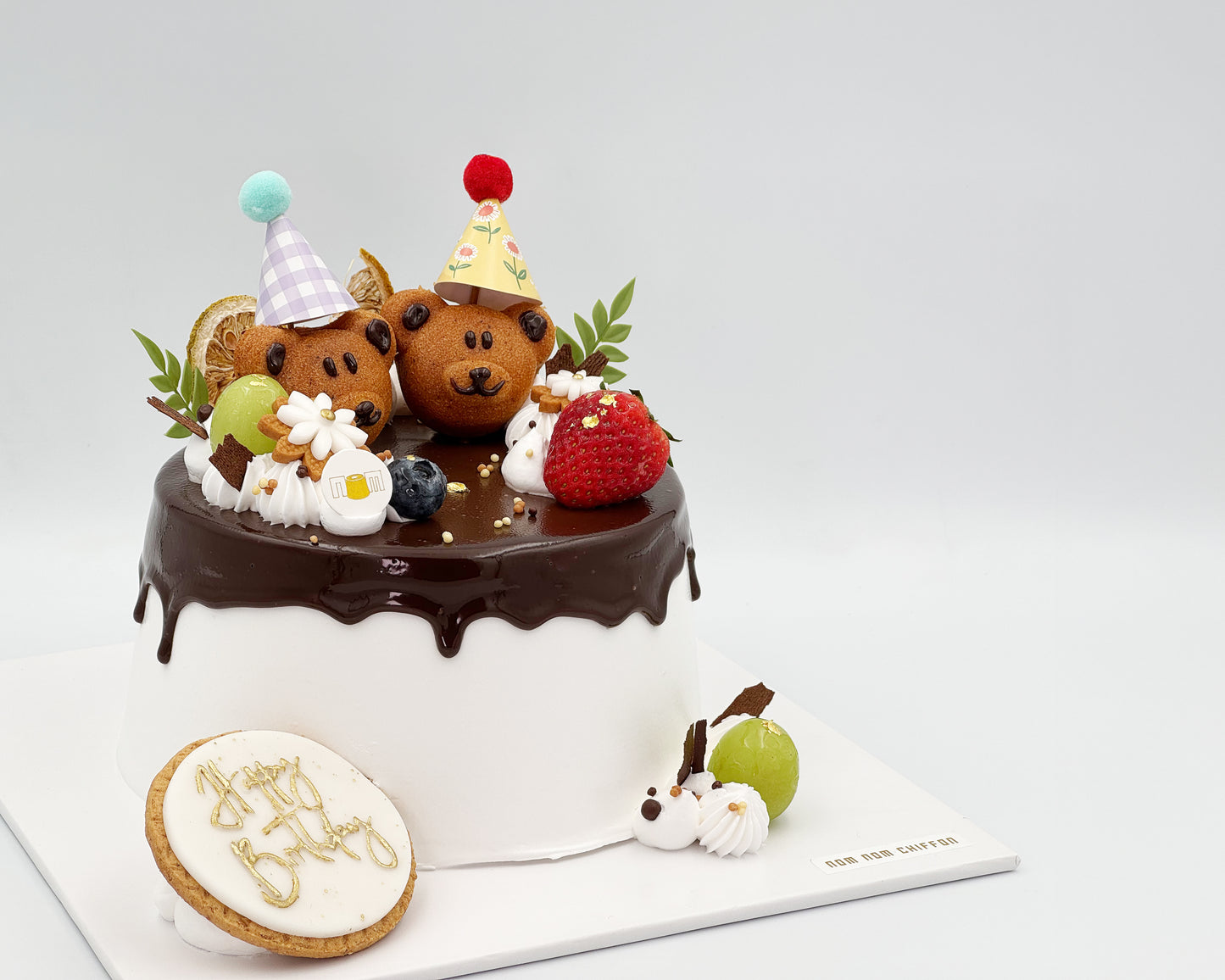 Decorative cake with teddy bear madeleines and a cookie on a white background