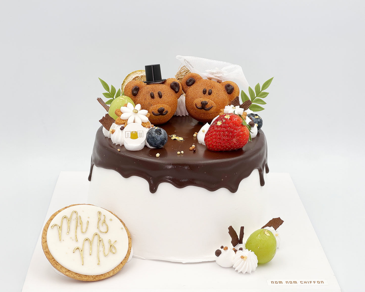 Chiffon cake with teddy bear madeleines and a 'Mr & Mrs' cookie on a white background