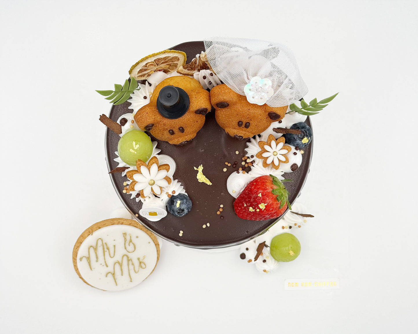 Top view of chiffon cake with teddy bear madeleines and fruit decorations on a white background