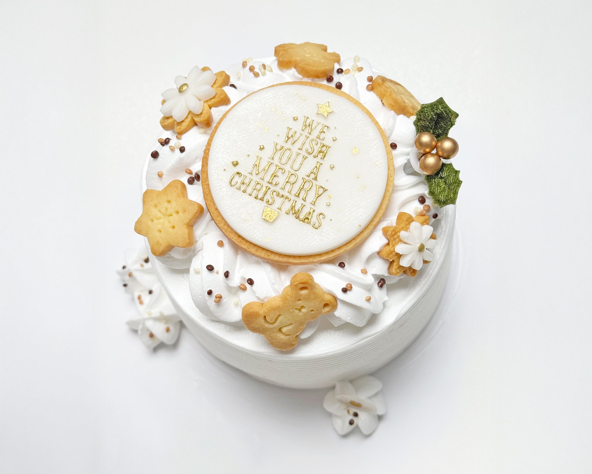 Side view of light, fluffy chiffon layered with soft cream, finished with a wreath of delicate cream swirls, handmade Christmas cookies, and a joyful holiday topper