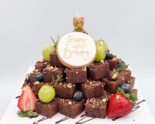 Brownie stacked cake with berries and a 'Happy Birthday' candle on a white background