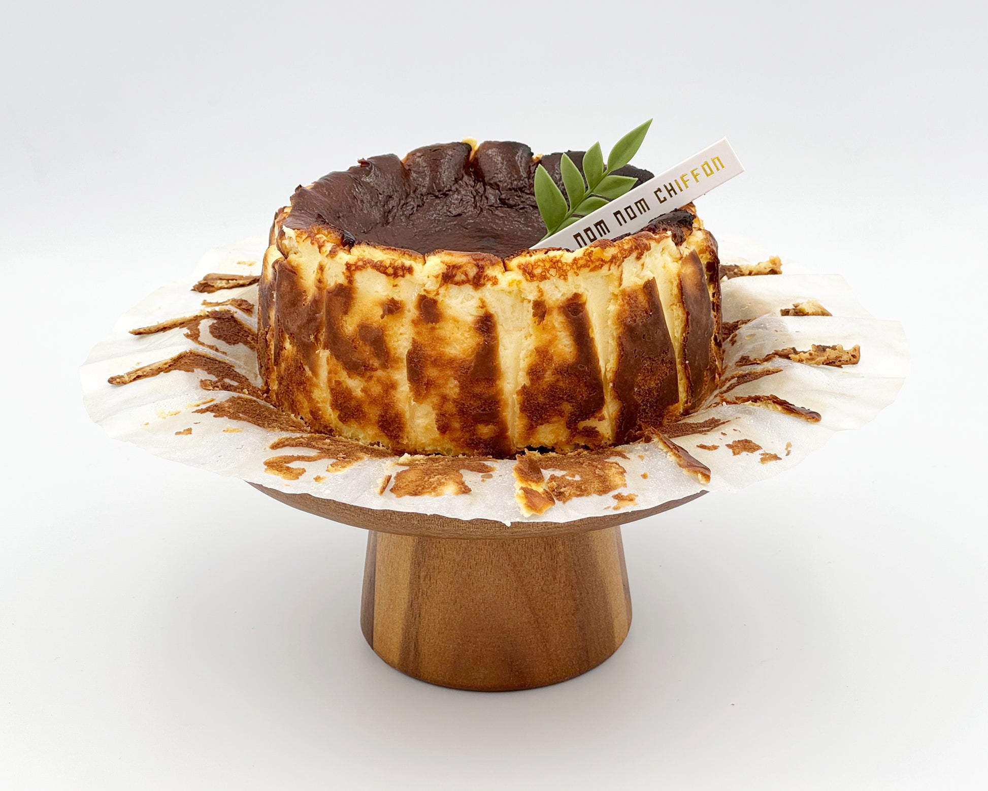 Basque burnt cheesecake on a wooden stand against a white background