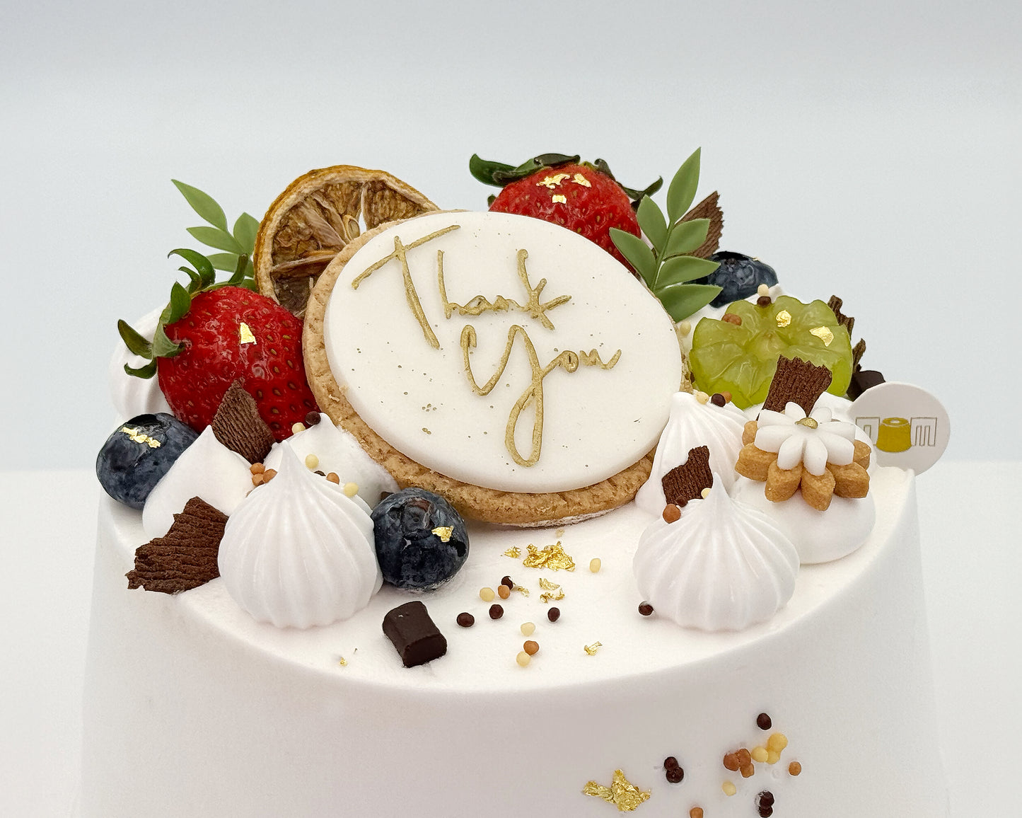 Close up of "Thank You" cake topper on a frosted chiffon cake