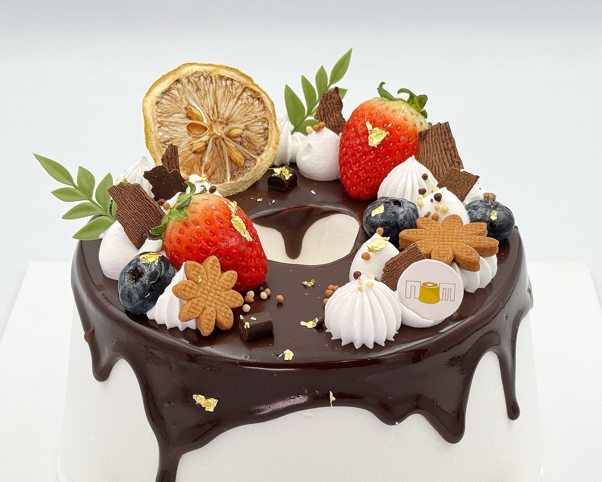 Close-up view of decorative chiffon cake with chocolate, strawberries, blueberries, and cookies on a white background