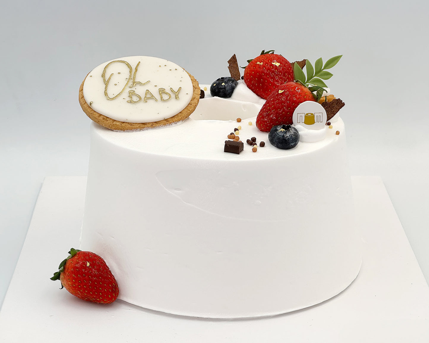 Baby shower cake with strawberries and cake topper on a white background