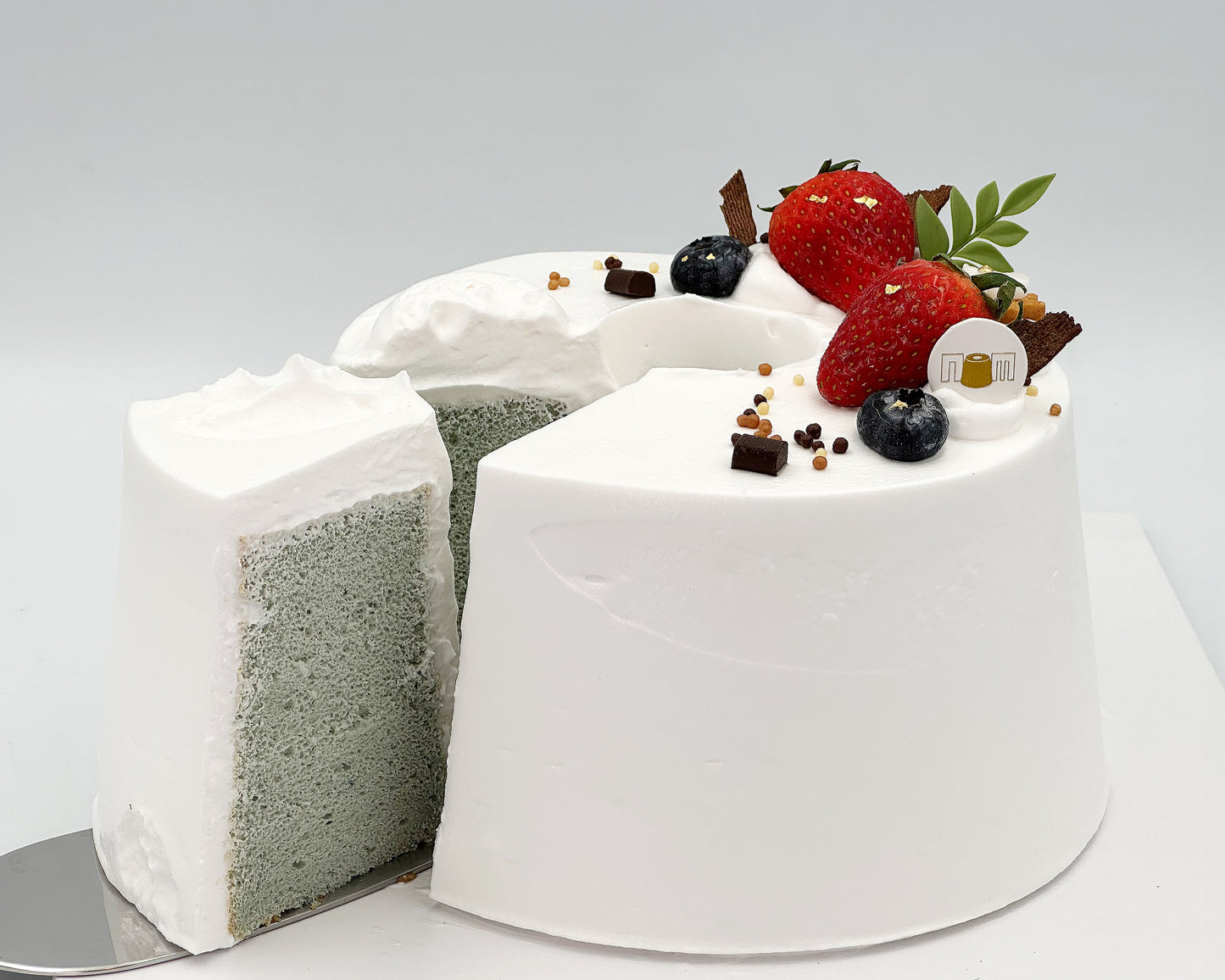 Gender reveal cake with white frosting and fruit on a gray background