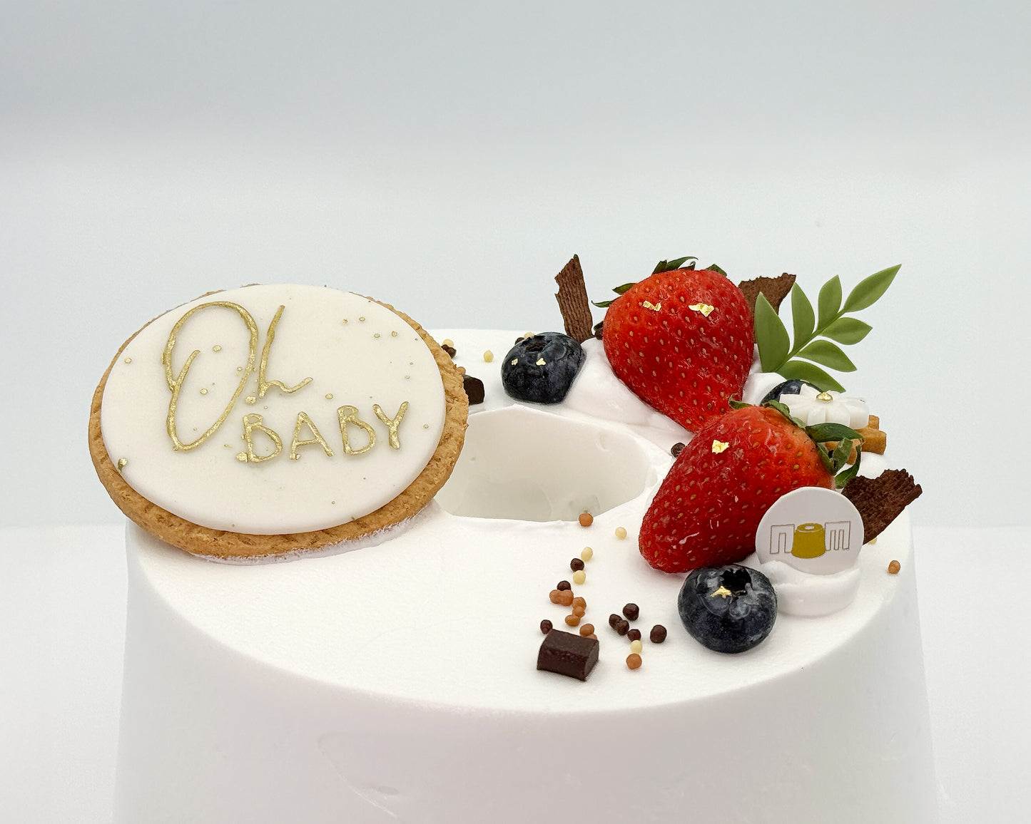 Close-up image with 'Oh Baby' decoration and fruit on a white background
