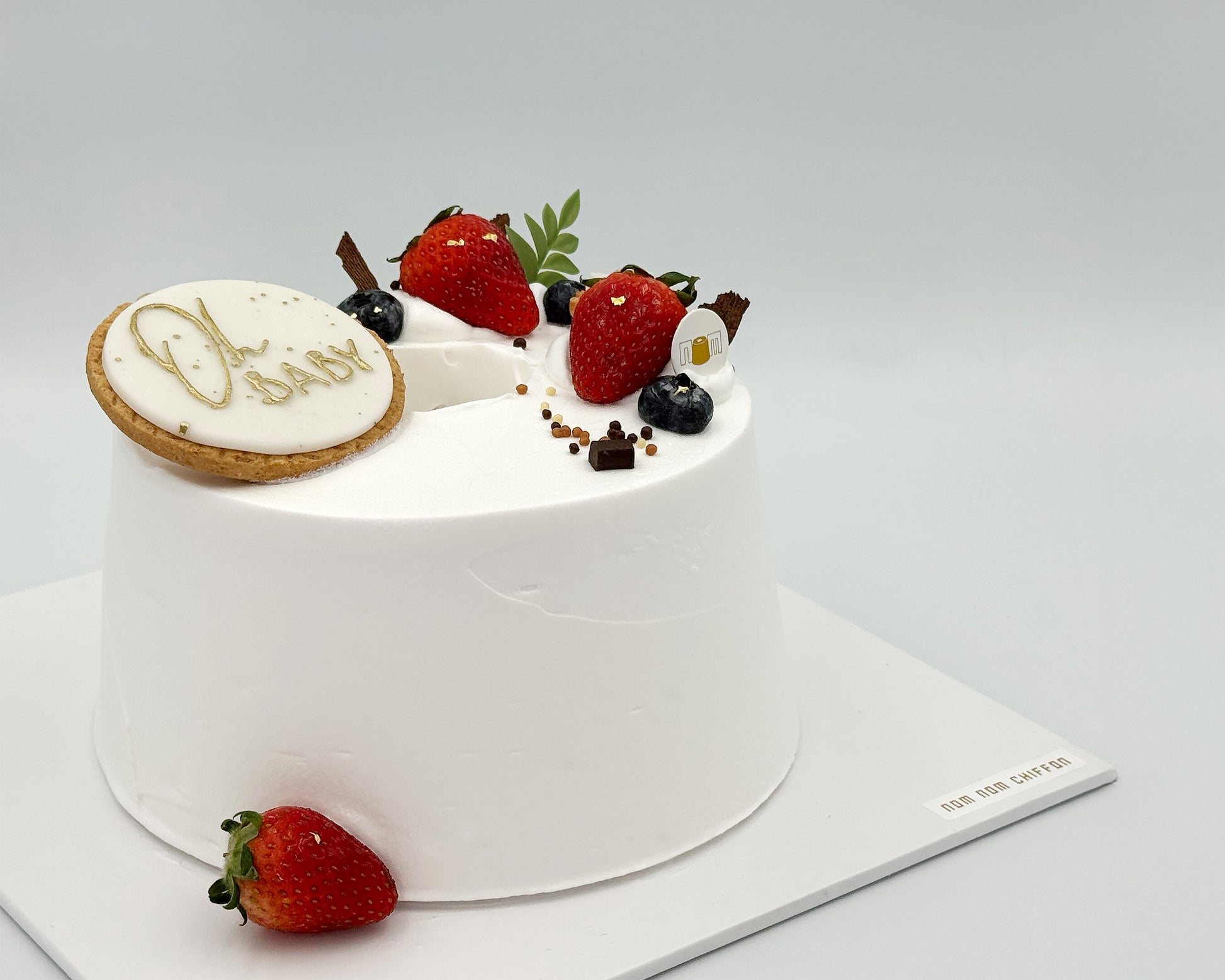 Small white cake with berries on a gray background