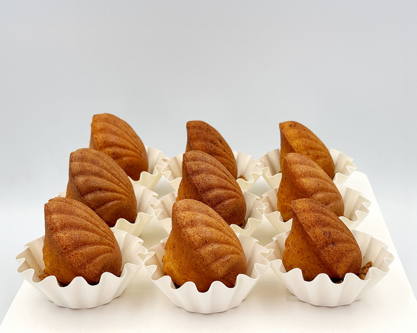 side profile of seashell madeleine, showing the pearls/humps, in white paper cups on a light gray background