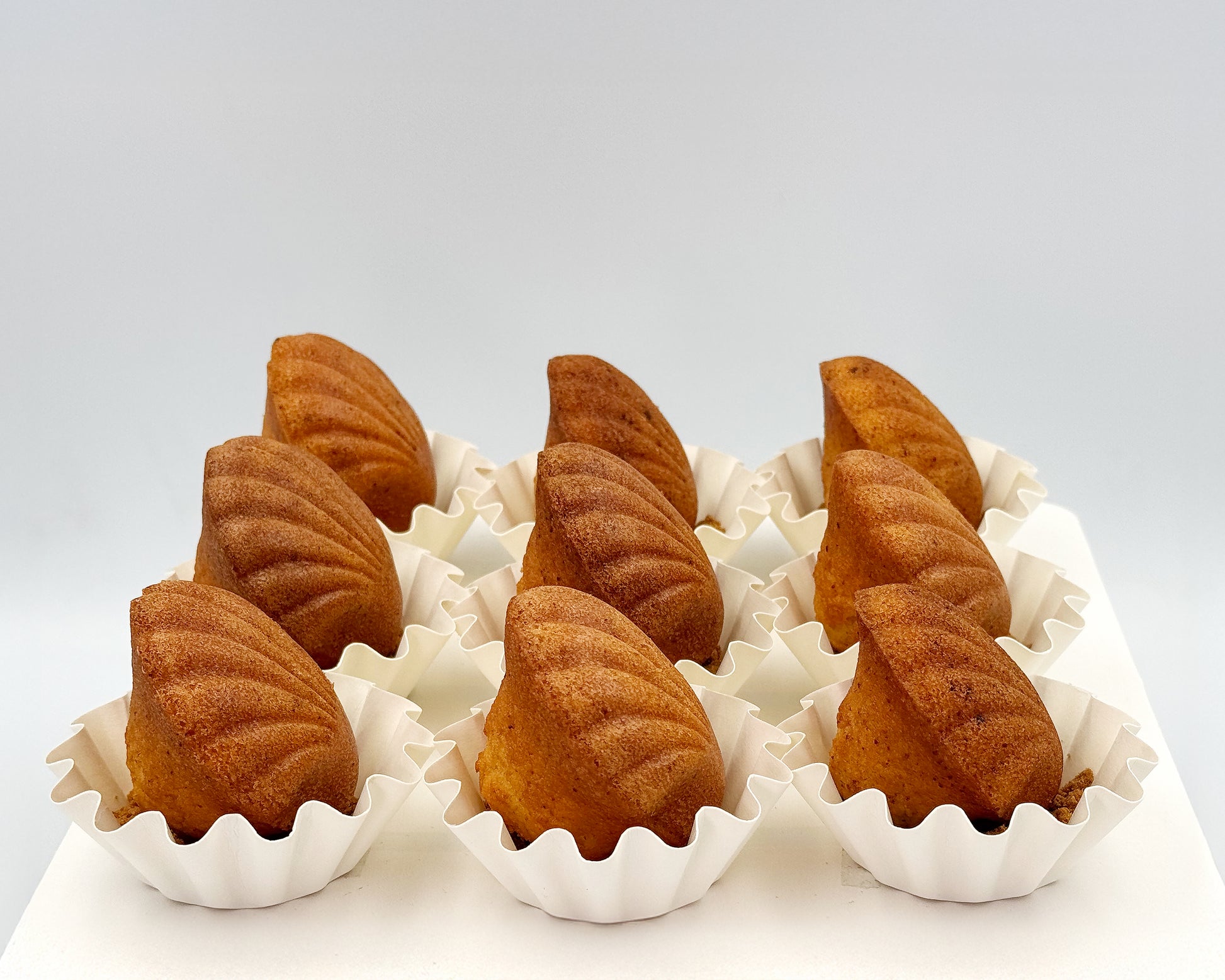 side profile of seashell madeleine, showing the pearls/humps, in white paper cups on a light gray background