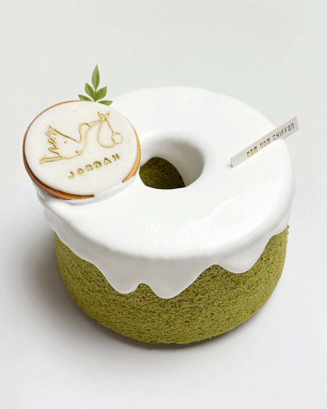 Green tea chiffon cake with snowcap, stork baby cake topper with 'JORDAN' name on a light gray background