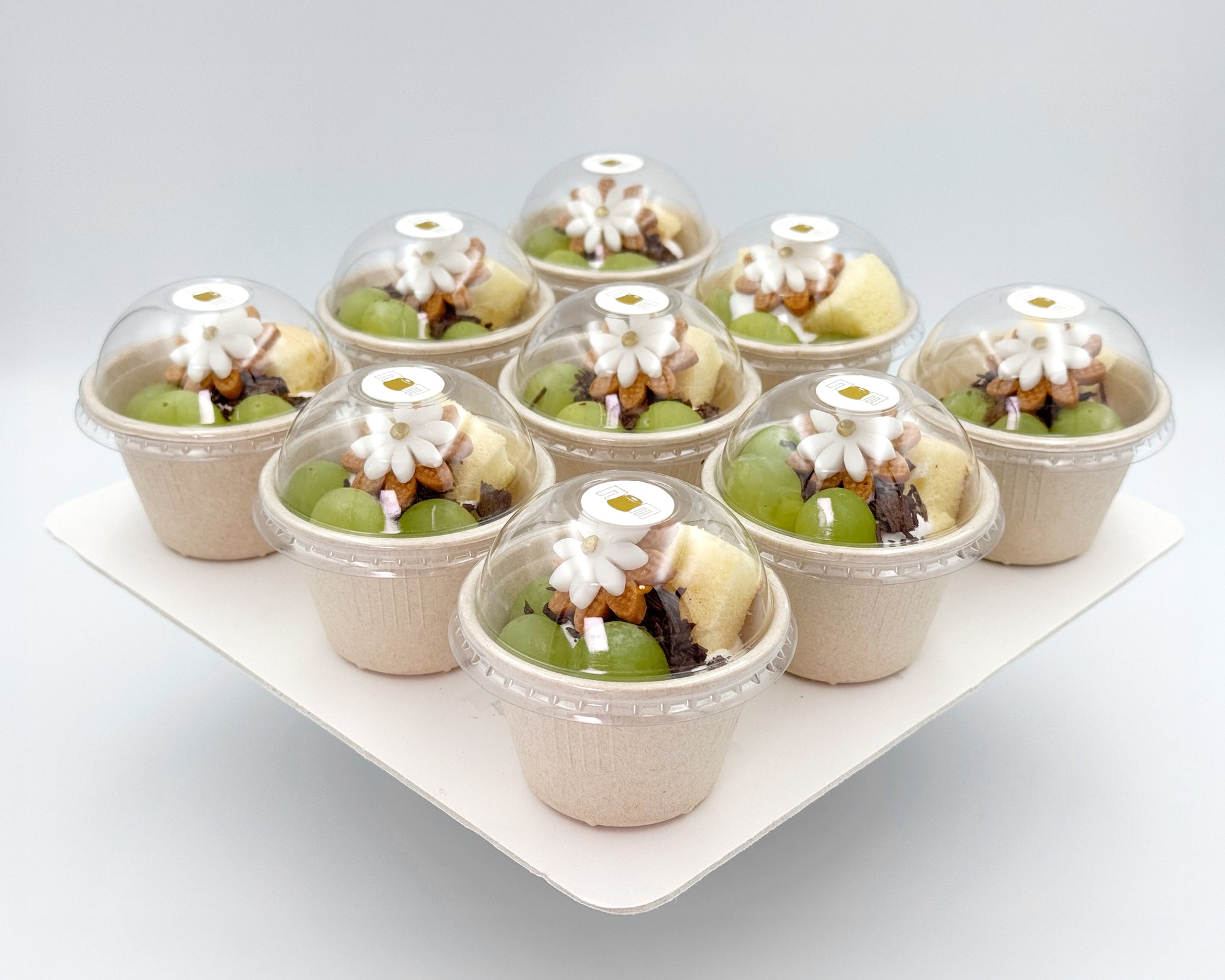 Petite chiffon cups in paper cups with clear domes on a white tray