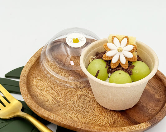 Petite chiffon cups with green grapes and a decorative cookie on a wooden plate.