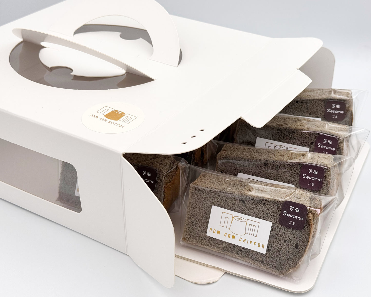 Black sesame chiffon cake in clear packaging with a white box on a light gray background