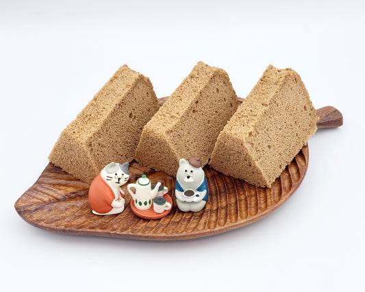 Earl grey chiffon cake slices on a wooden leaf-shaped plate with small figurines on a white background